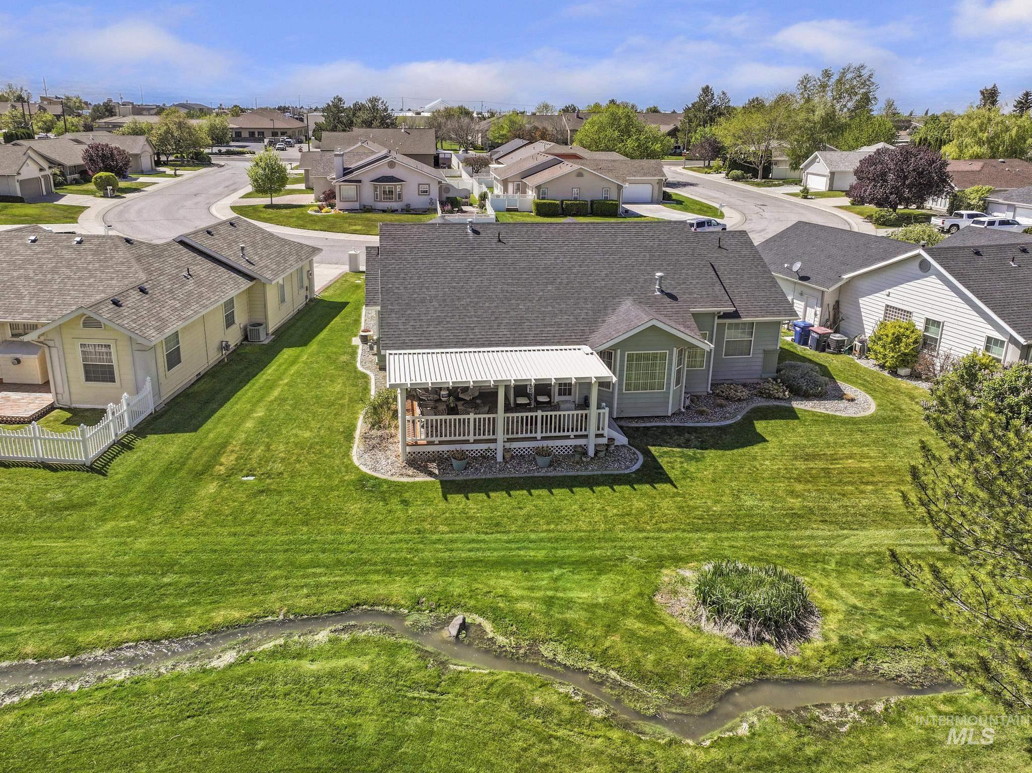 1558 Brookside Loop Twin Falls, ID 83301 - Photo 37 of 47 Expansive rear yard featuring a covered patio, manicured lawn, and a natural water feature