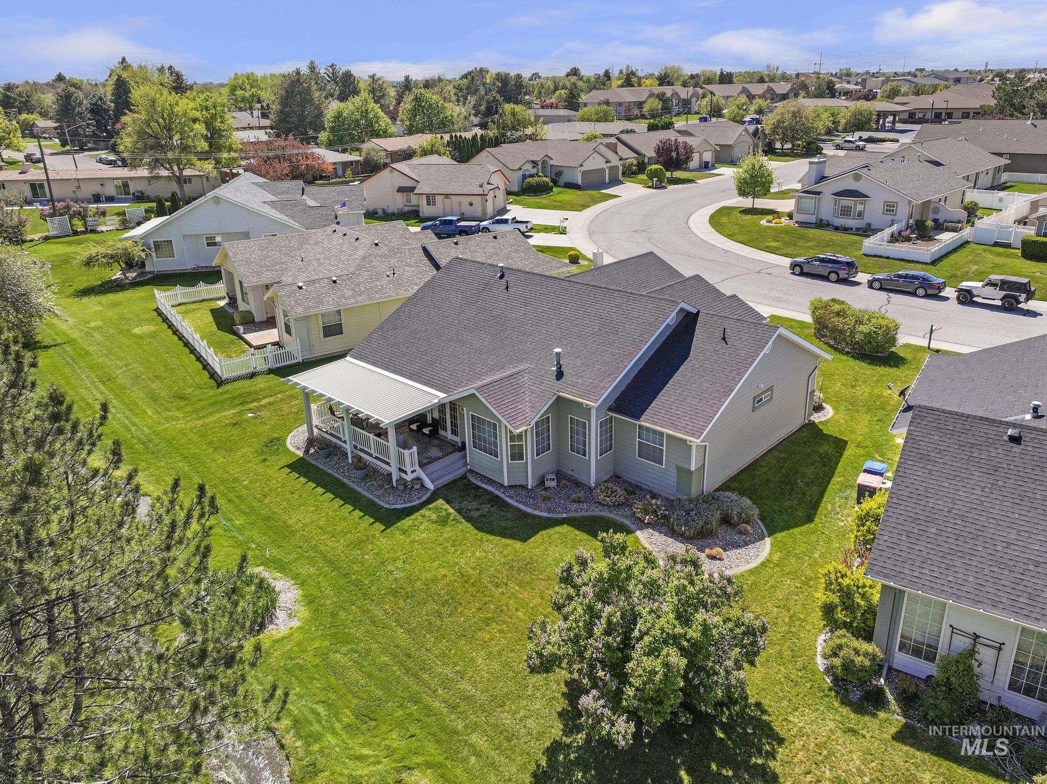 1558 Brookside Loop Twin Falls, ID 83301 - Photo 38 of 47 Rear elevation featuring a covered patio, extensive green lawn, landscaped beds, and a perimeter white picket fence