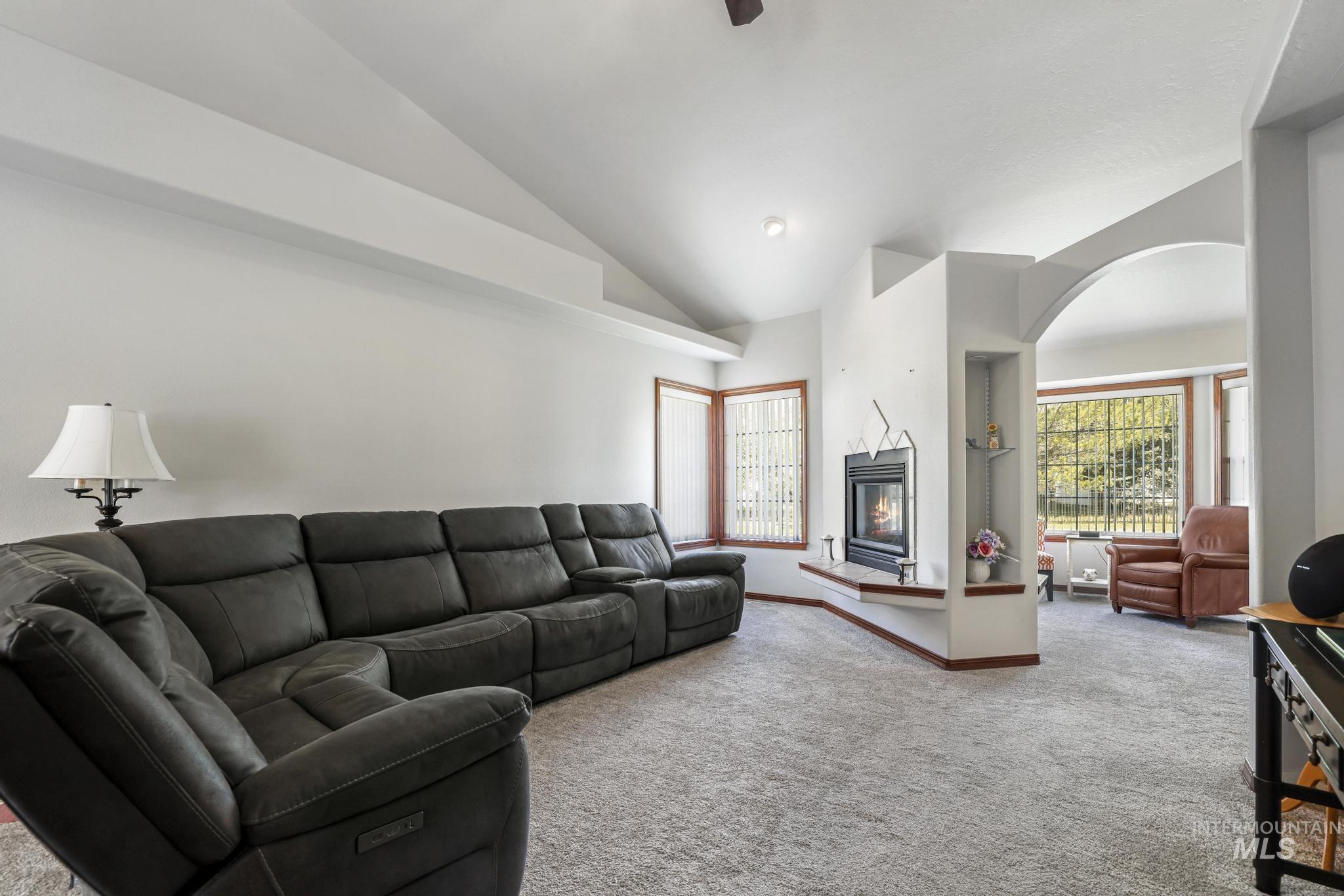 1558 Brookside Loop Twin Falls, ID 83301 - Photo 6 of 47 Living area featuring a fireplace with hearth, vaulted ceilings, and an arched doorway