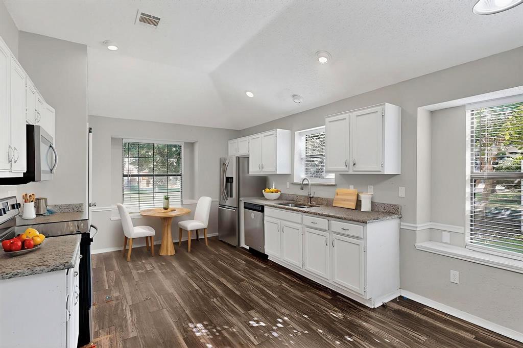 820 Charter Oak Street Allen, TX 75002 - Photo 18 of 37 Kitchen with stainless steel appliances, white cabinetry, dark wood-style flooring, recessed lighting, and light stone countertops