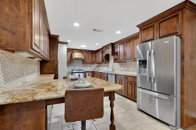 a kitchen with stainless steel appliances granite countertop a refrigerator a stove a sink and a microwave