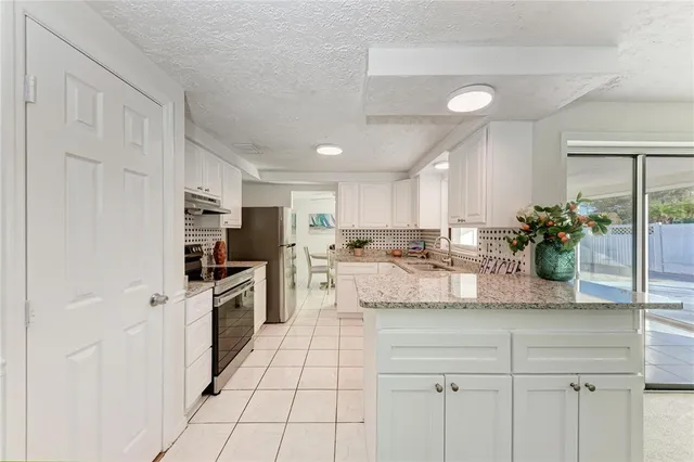 a kitchen with stainless steel appliances kitchen island granite countertop a refrigerator and a sink