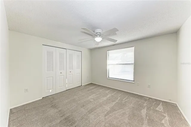 an empty room with windows and ceiling fan