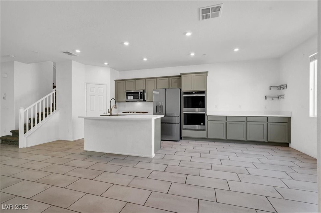 8033 Skye Foxx Street Las Vegas, NV 89166 - Photo 2 of 25 Kitchen featuring appliances with stainless steel finishes, a kitchen island with sink, recessed lighting, gray cabinets, and light tile patterned flooring