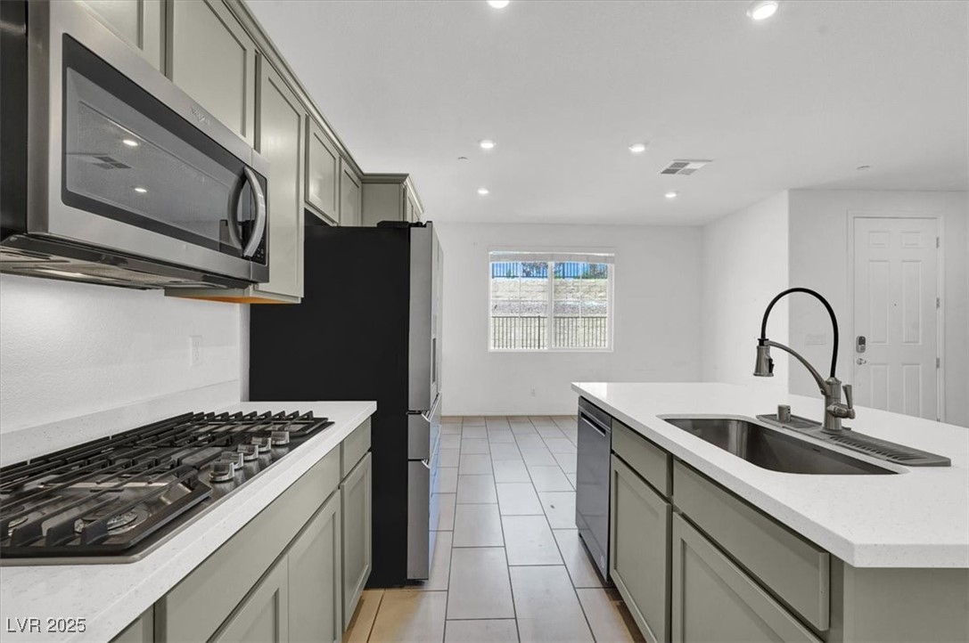 8033 Skye Foxx Street Las Vegas, NV 89166 - Photo 4 of 25 Kitchen with gray cabinets, appliances with stainless steel finishes, light stone counters, recessed lighting, and an island with sink