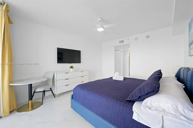 a spacious bedroom with a bed and a flat screen tv