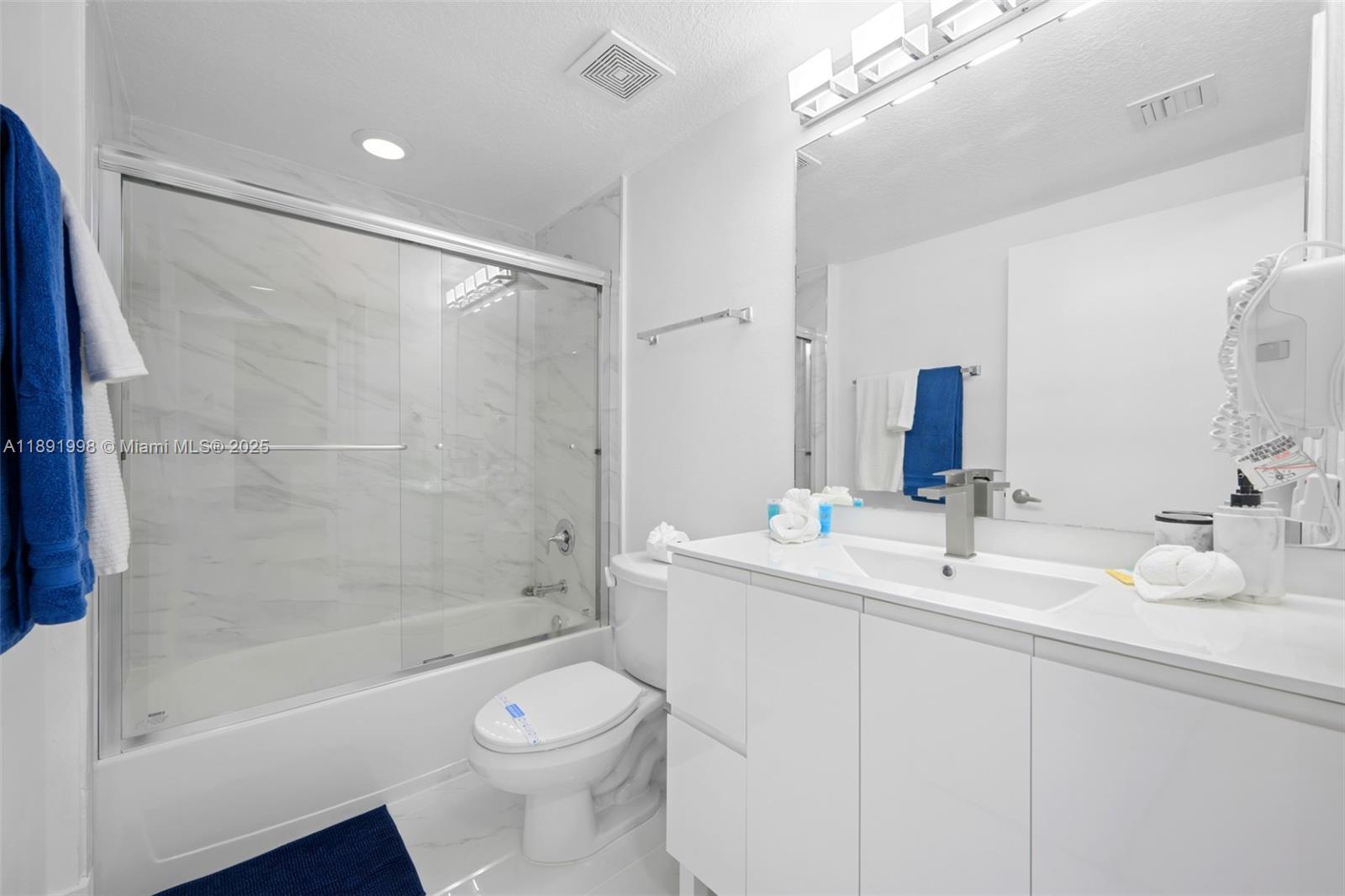 18100 North Bay Road, Unit 708 Sunny Isles Beach, FL 33160 - Photo 21 of 26 a bathroom with a double vanity sink toilet mirror and shower