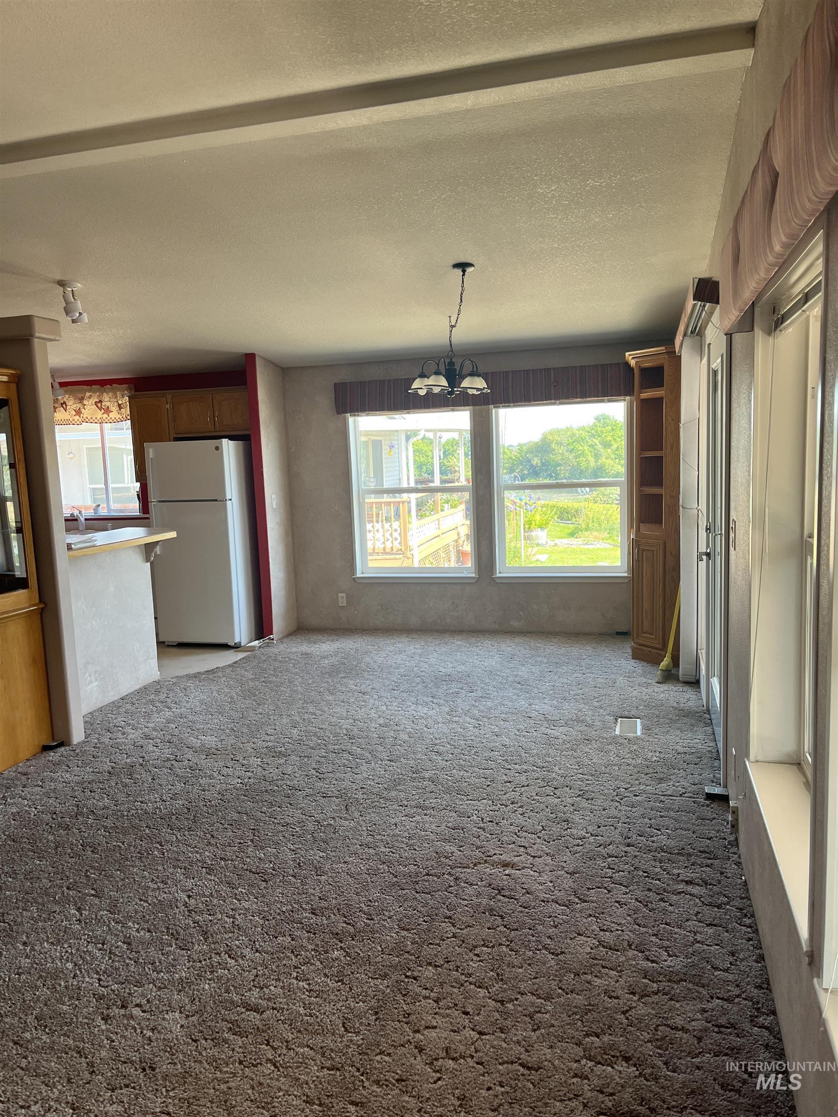 2750 Alden Road, Unit 34 Fruitland, ID 83619 - Photo 18 of 41 Unfurnished living room featuring carpet flooring, a textured ceiling, and a chandelier