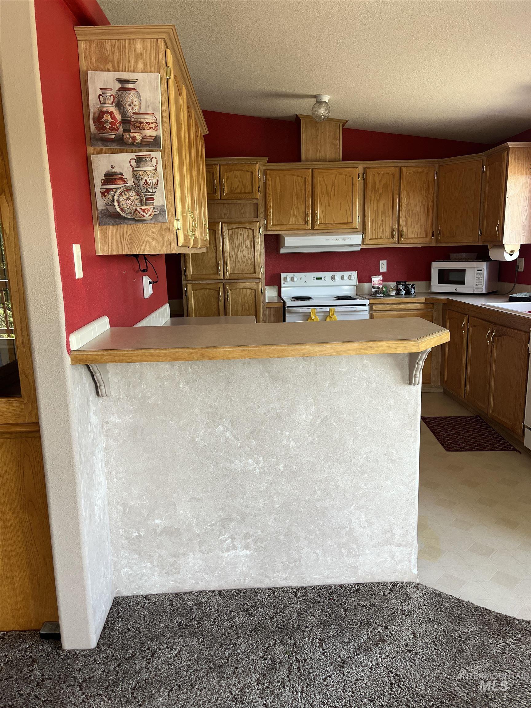 2750 Alden Road, Unit 34 Fruitland, ID 83619 - Photo 20 of 41 Kitchen featuring light countertops, brown cabinetry, white appliances, a peninsula, and a textured ceiling