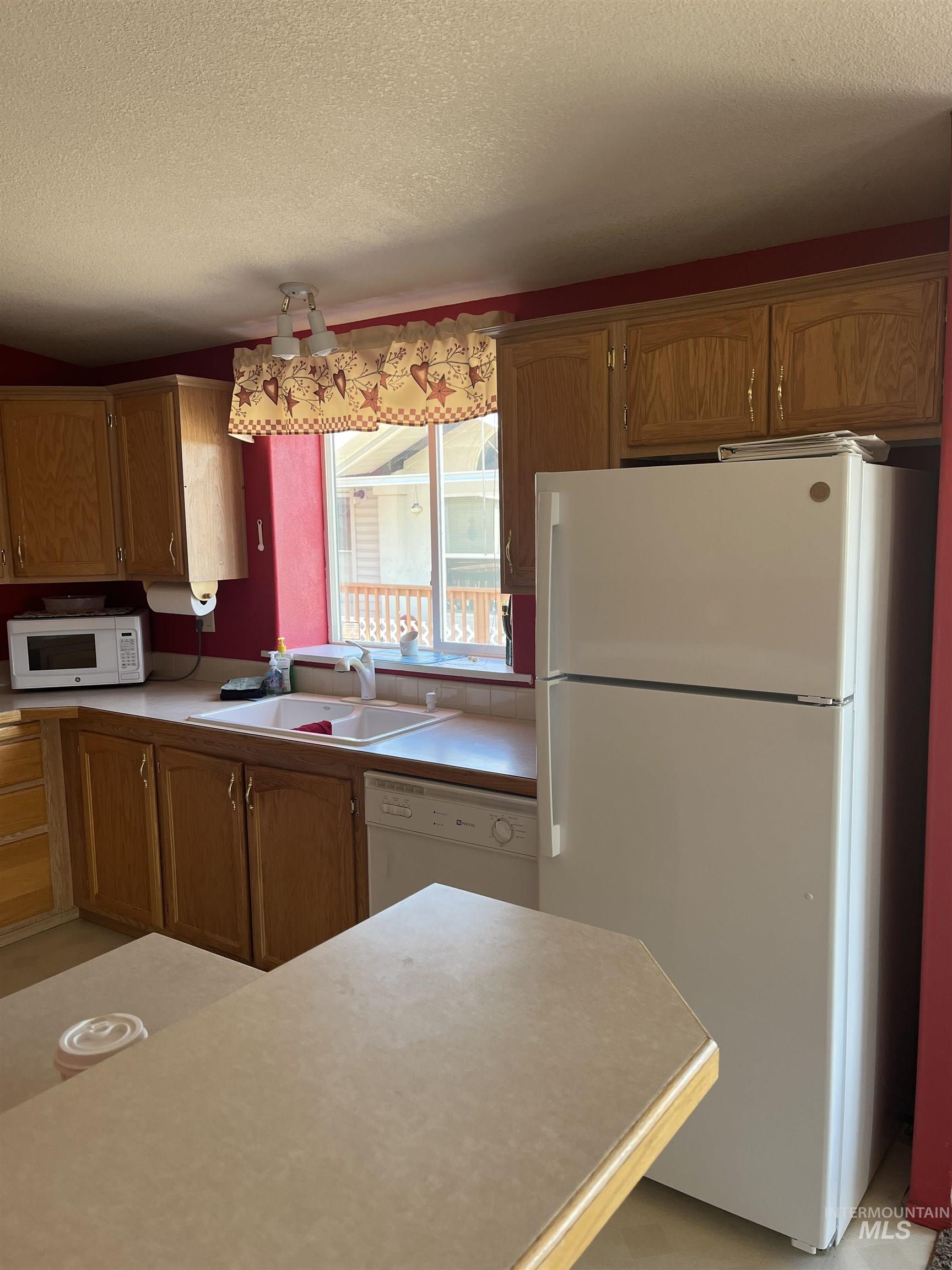 2750 Alden Road, Unit 34 Fruitland, ID 83619 - Photo 21 of 41 Kitchen with white appliances, a textured ceiling, light countertops, and brown cabinetry