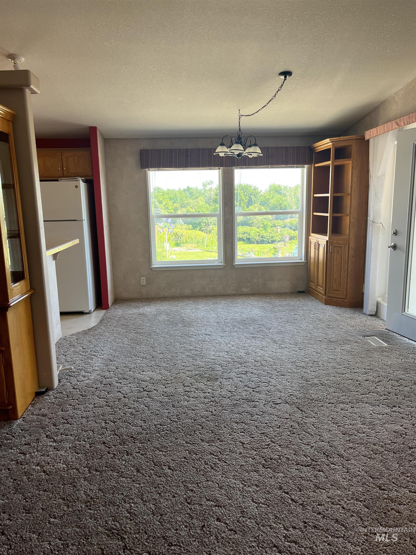 2750 Alden Road, Unit 34 Fruitland, ID 83619 - Photo 37 of 41 Unfurnished living room featuring light colored carpet, a textured ceiling, and a chandelier