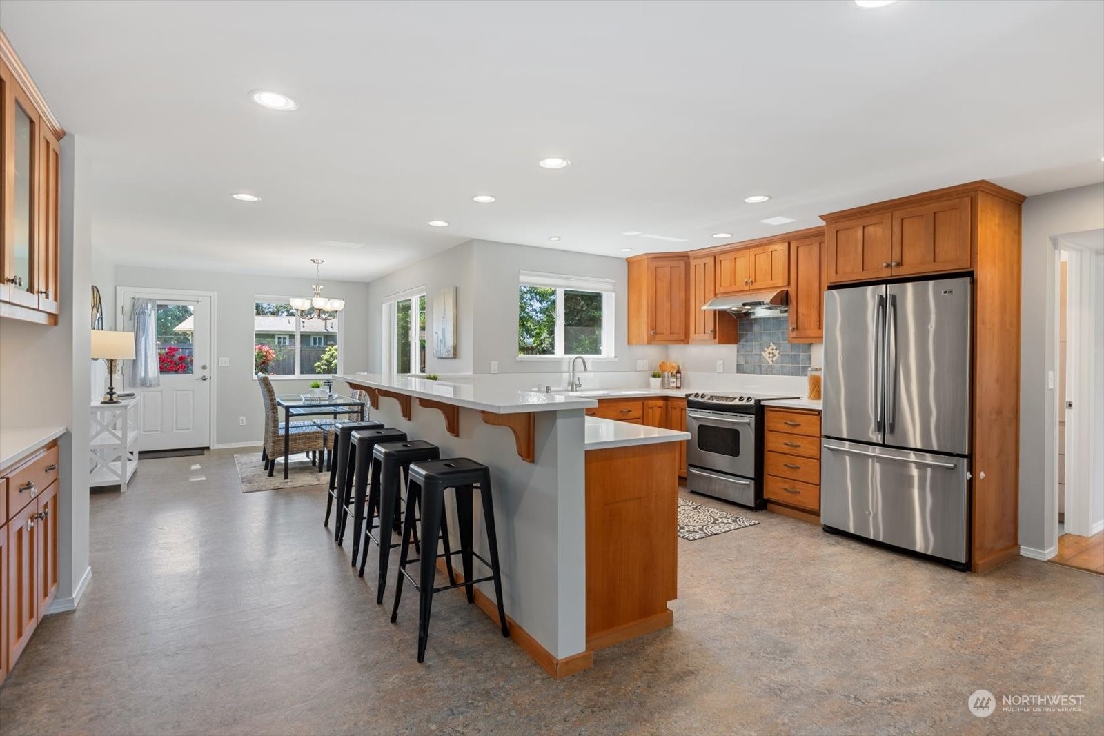 8630 217th Street Southwest Edmonds, WA 98026 - Photo 15 of 34 a kitchen with stainless steel appliances kitchen island granite countertop a refrigerator a stove a sink a dining table and chairs