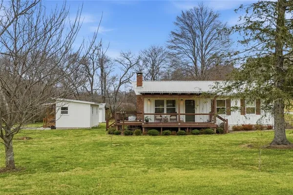 a front view of a house with a garden and trees