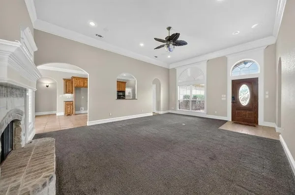 a view of a livingroom with a fireplace a ceiling fan and windows