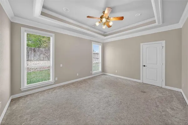 an empty room with windows and chandelier fan