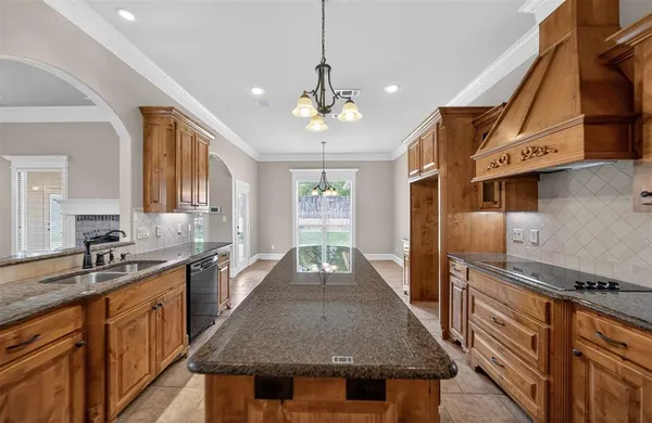 a kitchen with granite countertop stainless steel appliances a sink dishwasher a stove a refrigerator a sink dishwasher and wooden cabinets with wooden floor
