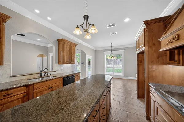 a large kitchen with granite countertop a large island in the center and stainless steel appliances