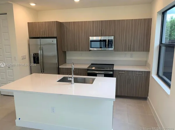 a kitchen with a sink a counter top space stainless steel appliances and cabinets