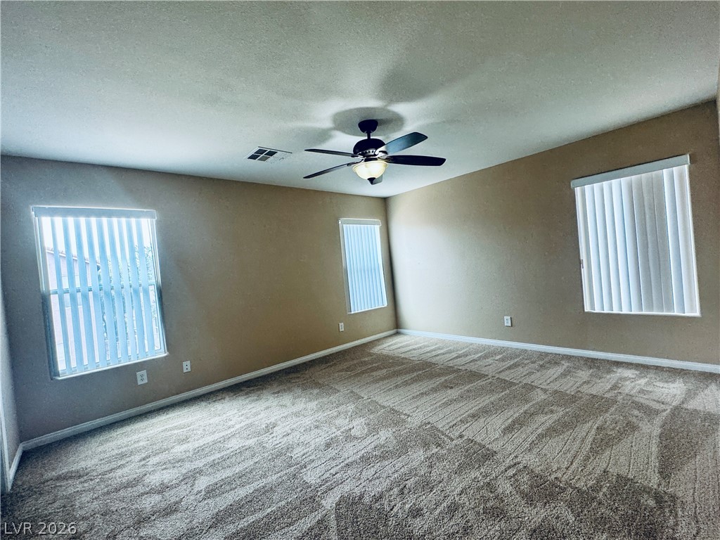 8617 Palomino Ranch Street Las Vegas, NV 89131 - Photo 19 of 27 An airy primary bedroom features plush carpeting, neutral walls, and a ceiling fan.