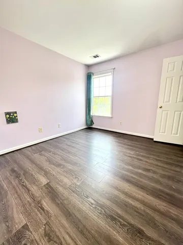an empty room with wooden floor and window
