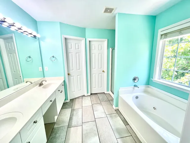 a spacious bathroom with a tub sink and mirror