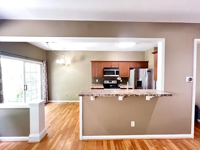 a living room with stainless steel appliances kitchen island a flat screen tv and a sink