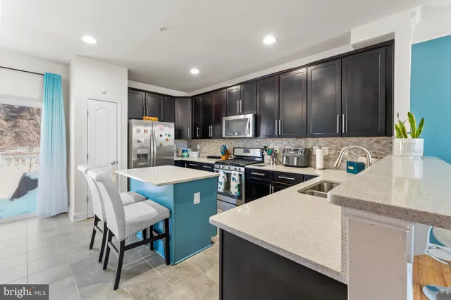 a kitchen with a sink a microwave a refrigerator and chairs