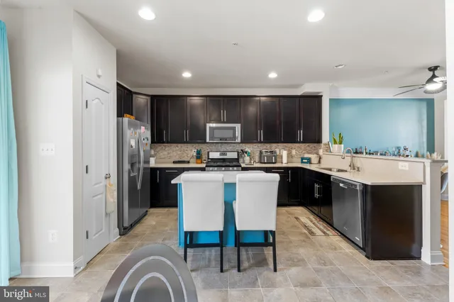 a kitchen with kitchen island granite countertop a sink a stove a refrigerator and chairs