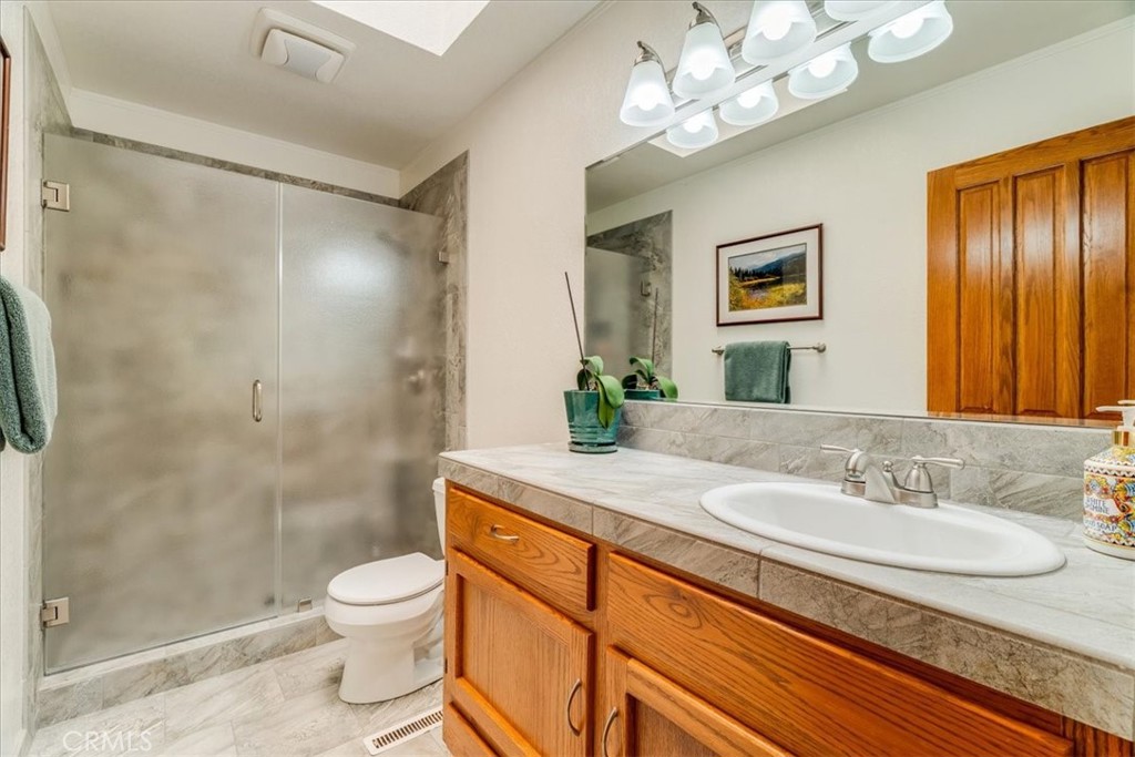 11555 Cenegal Road Atascadero, CA 93422 - Photo 35 of 57 a bathroom with a granite countertop sink a toilet a mirror and shower