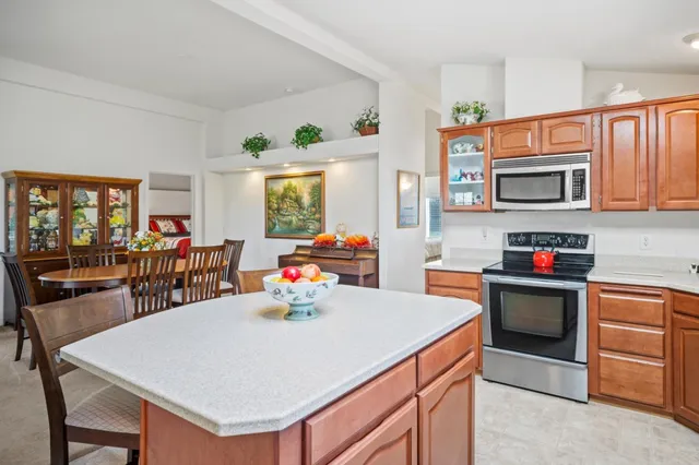 a kitchen with stainless steel appliances a stove a sink a microwave a dining table and chairs