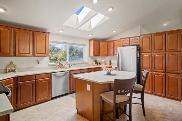 a kitchen with stainless steel appliances granite countertop a dining table chairs refrigerator sink and cabinets