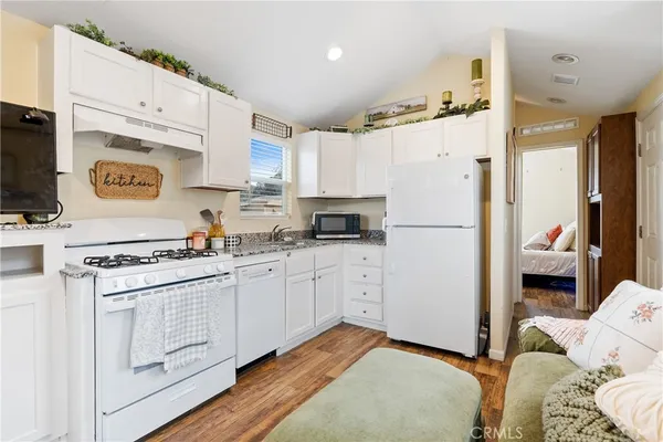 a kitchen with cabinets appliances and wooden floor