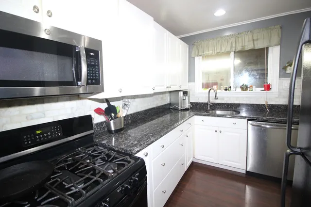 a kitchen with stainless steel appliances granite countertop a stove a sink and a microwave