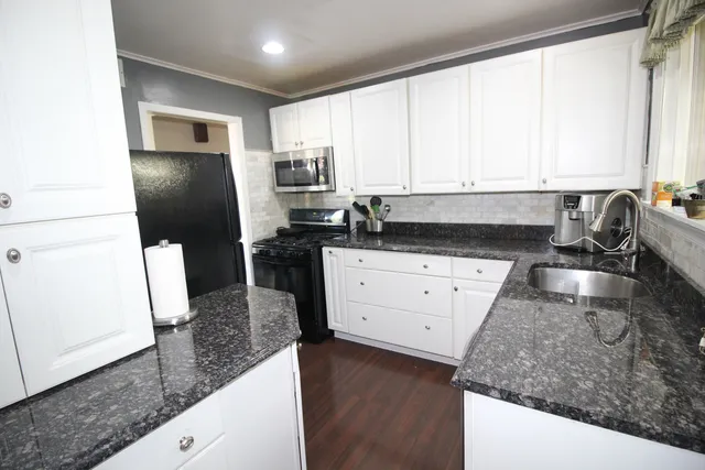 a kitchen with granite countertop white cabinets and stainless steel appliances
