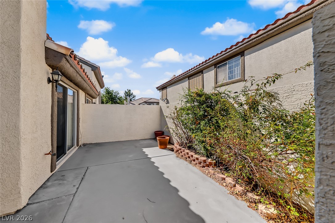 205 Genesee Point Street Henderson, NV 89074 - Photo 4 of 30 An enclosed concrete patio creates a private outdoor retreat alongside stucco walls.