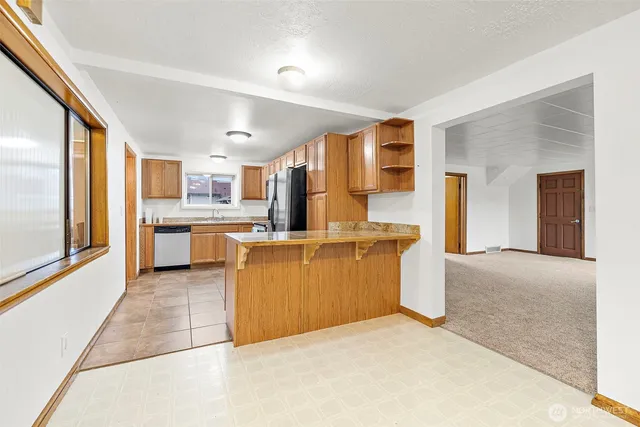 a large open kitchen with a refrigerator a stove top oven a sink and dishwasher