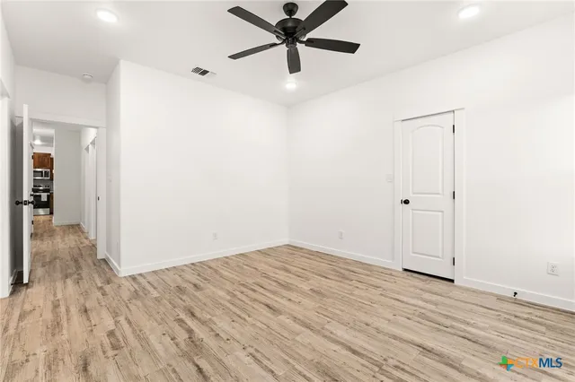 an empty room with wooden floor and windows
