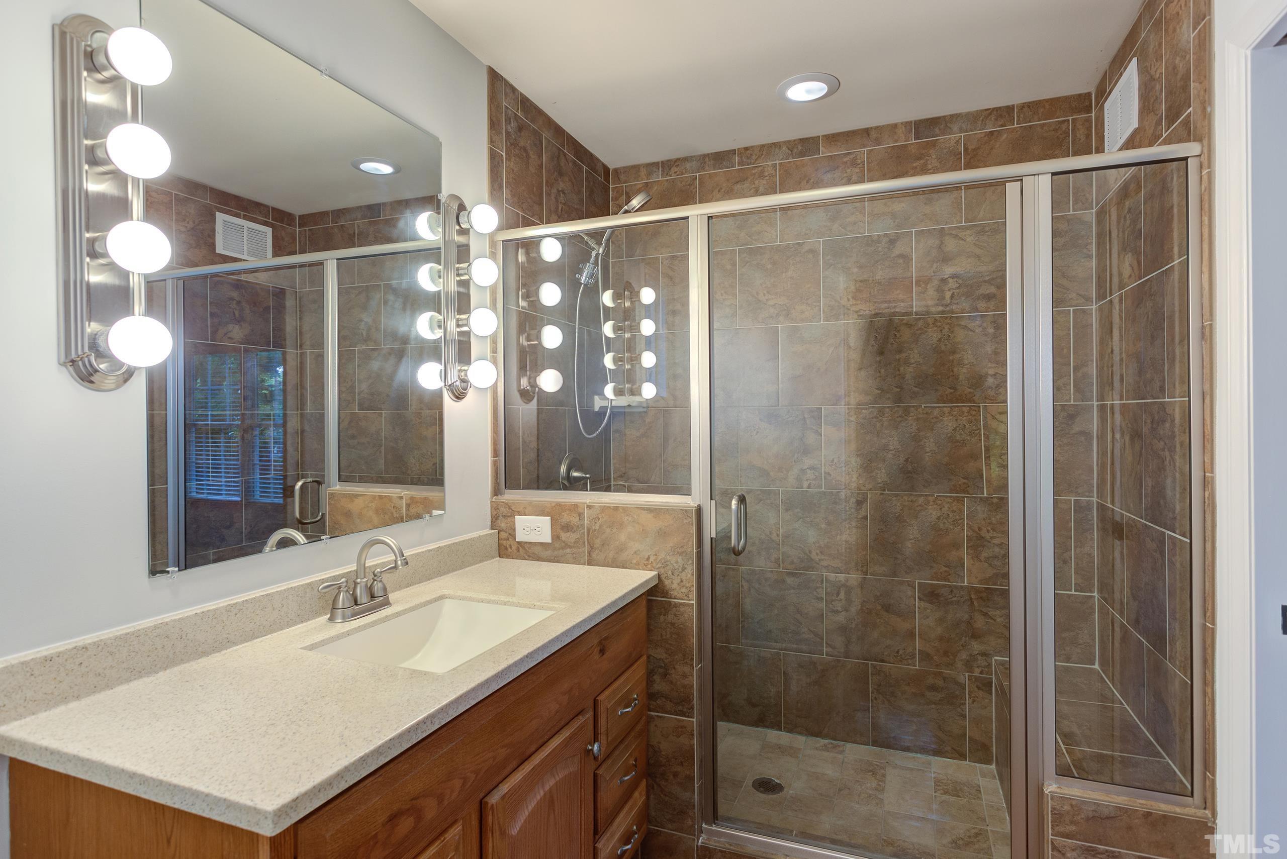2312 Gresham Lake Road Raleigh, NC 27615 - Photo 18 of 46 a bathroom with a shower sink vanity and mirror