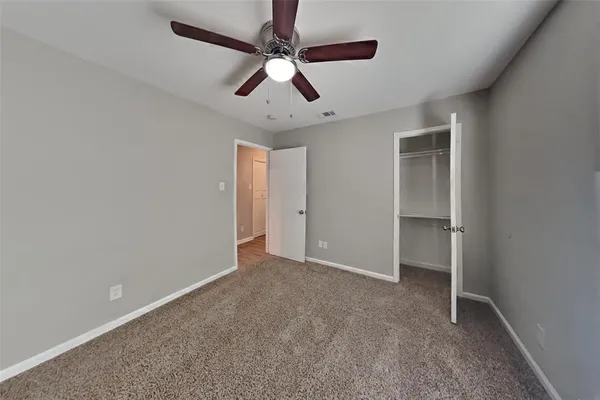 an empty room with a ceiling fan and carpet
