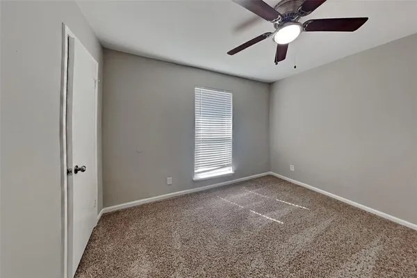 an empty room with a chandelier fan and windows