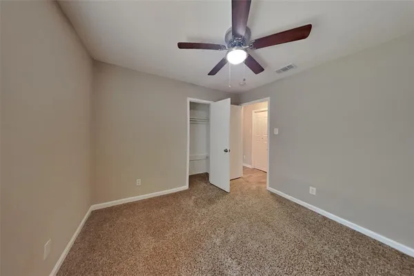 an empty room with a chandelier fan and a ceiling fan