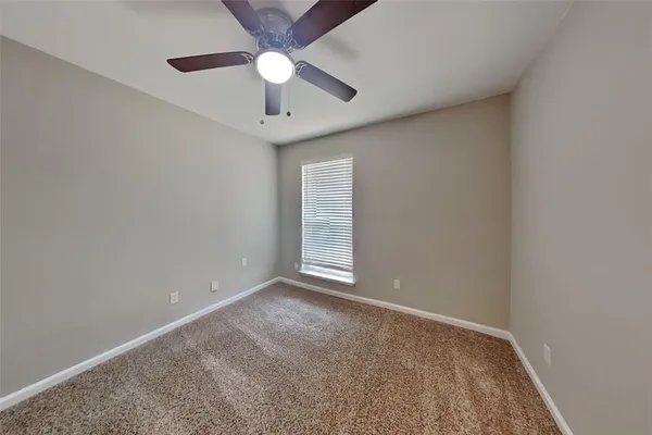an empty room with a ceiling fan and carpet