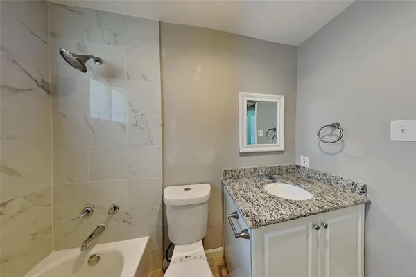 a bathroom with a granite countertop sink a toilet and shower