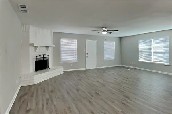 an empty room with wooden floor cabinet and windows