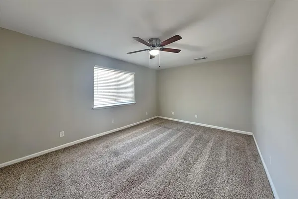 an empty room with a window and a ceiling fan