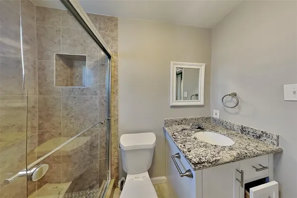 a bathroom with a granite countertop sink a toilet and shower