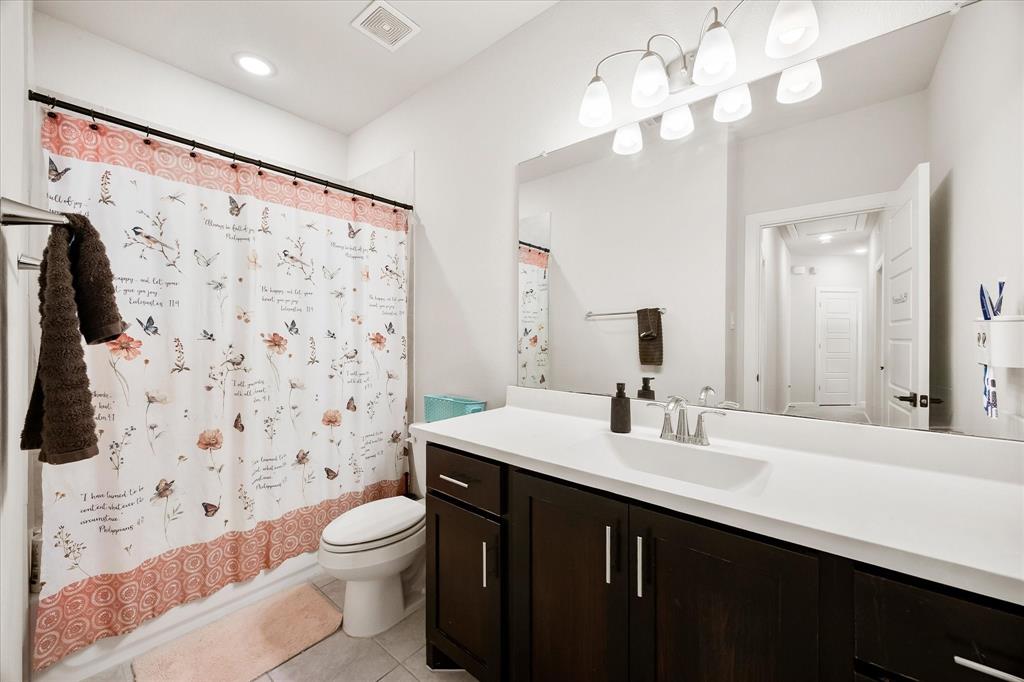 9224 Lamar Street Rowlett, TX 75089 - Photo 19 of 27 Bathroom featuring a single vanity with a dark wood-finish cabinet and white countertop, an integrated sink, and a wall-mounted mirror