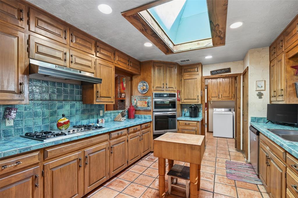 3030 Wager Road Flower Mound, TX 75028 - Photo 16 of 39 a kitchen with stainless steel appliances kitchen island granite countertop a table chairs in it and wooden floors