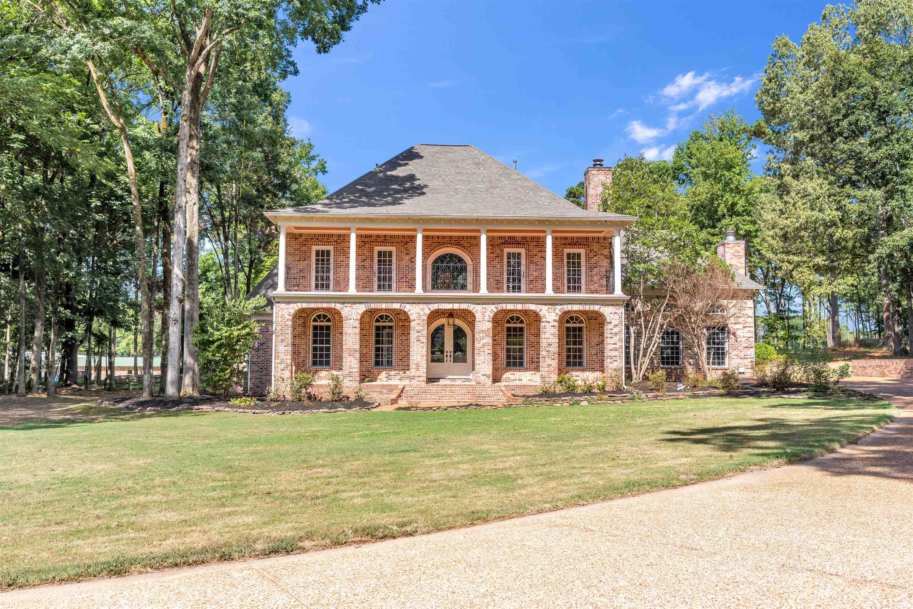 View of front of property featuring a porch, brick siding, a front lawn, and a chimney
