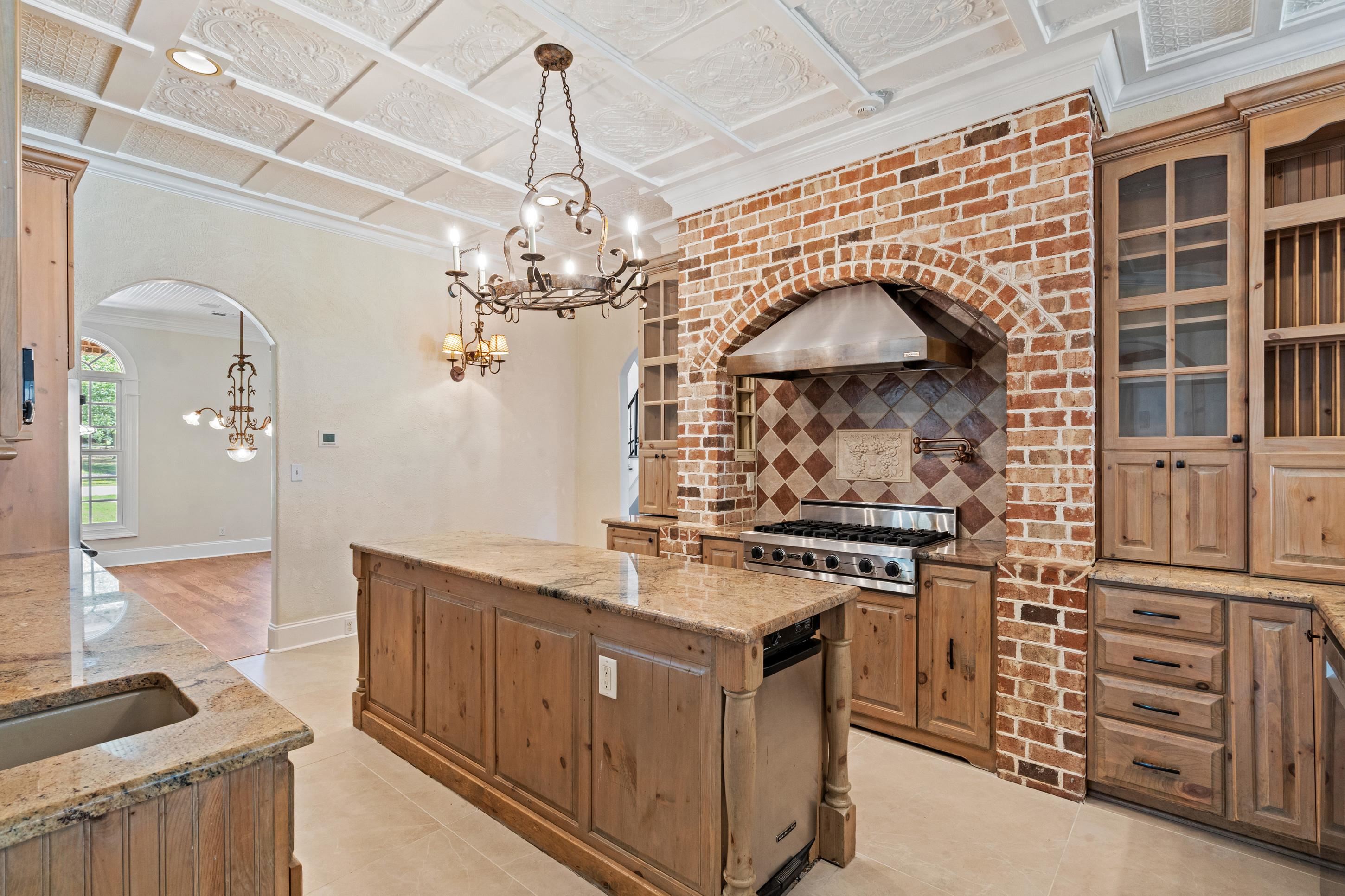 815 Dent Road Eads, TN 38028 - Photo 12 of 40 Kitchen with a kitchen island, light stone counters, arched walkways, a chandelier, and ornamental molding